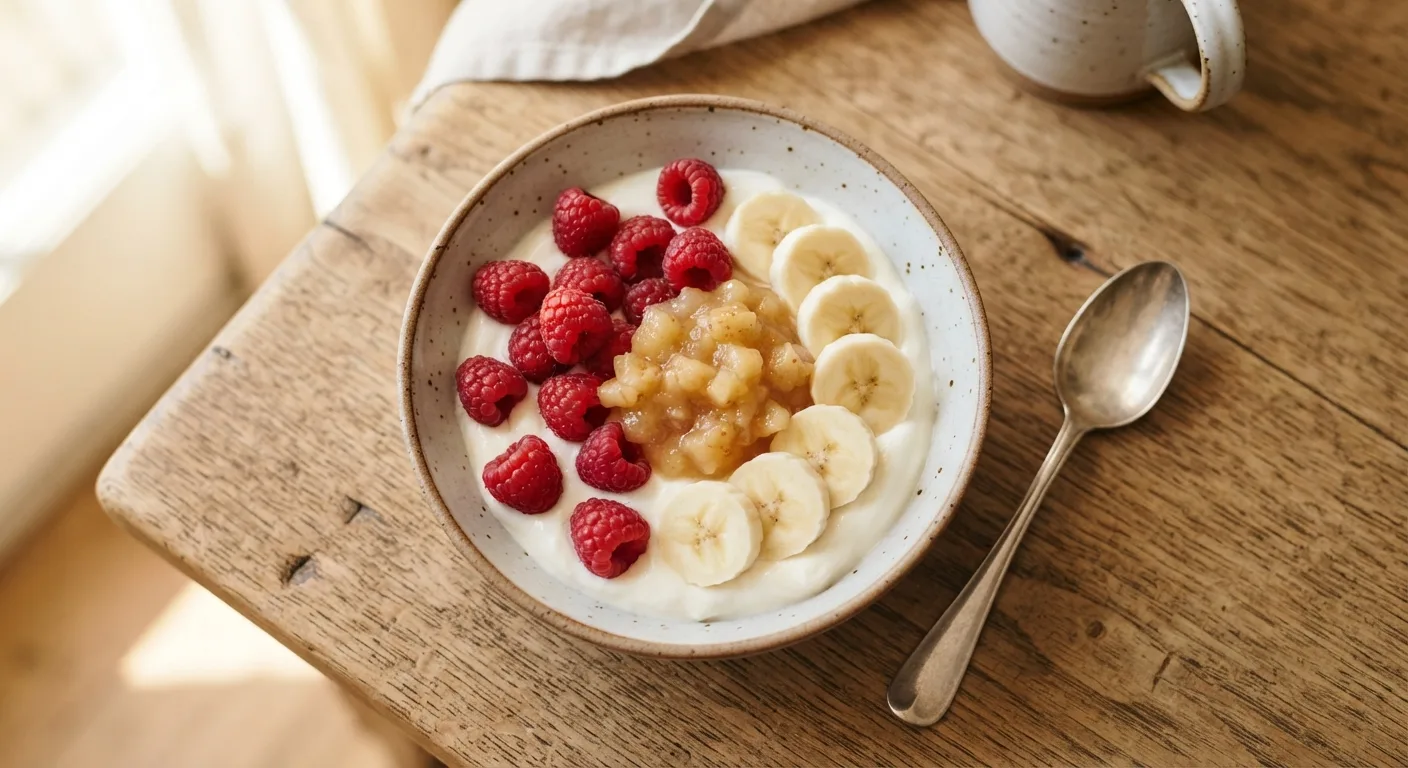 Un bol de laitage nature garni de fruits frais et d'une cuillère de compote
