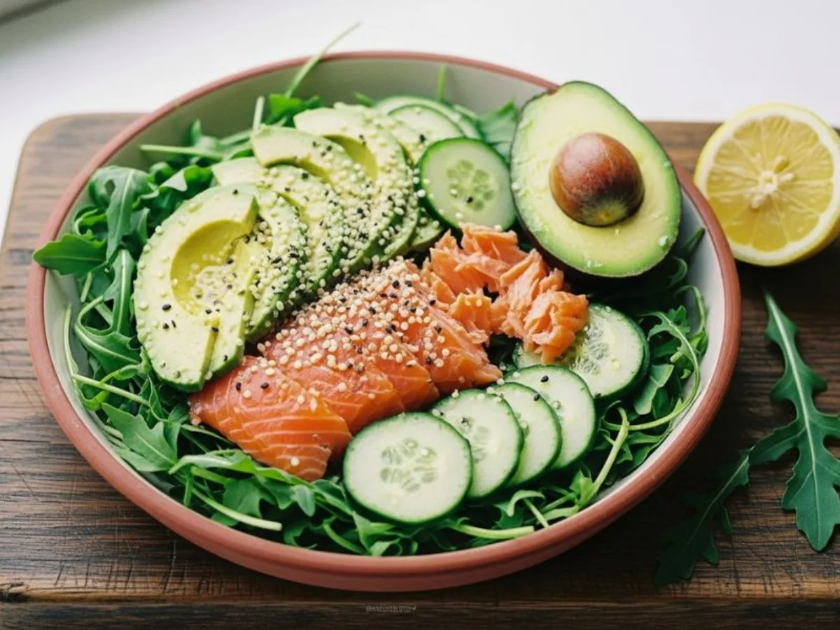 Salade de saumon et avocat sur un lit de roquette, avec concombre, graines de chanvre et quartier de citron